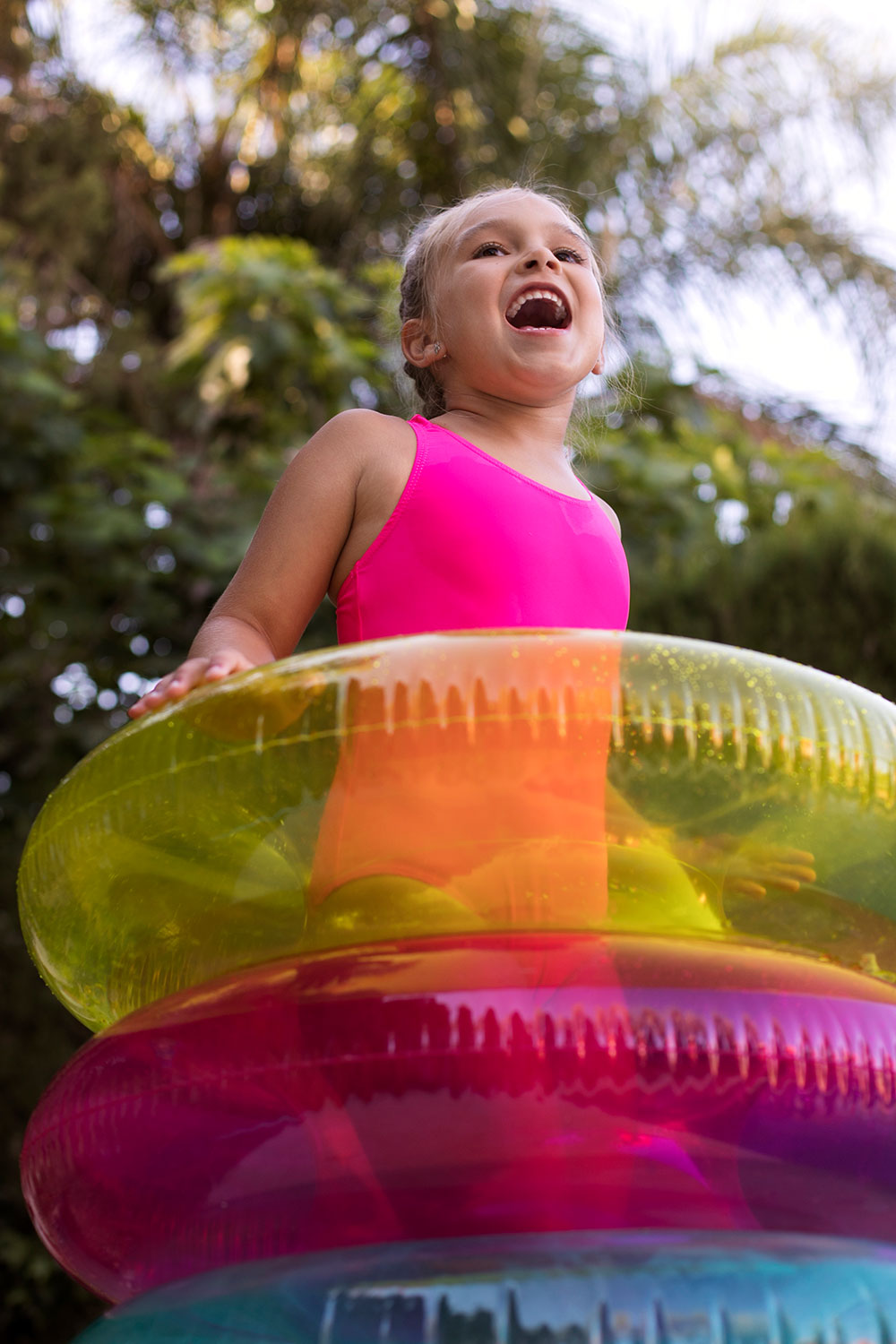 bimba con tre salvagenti colorati che si sta divertendo in un parco acquatico