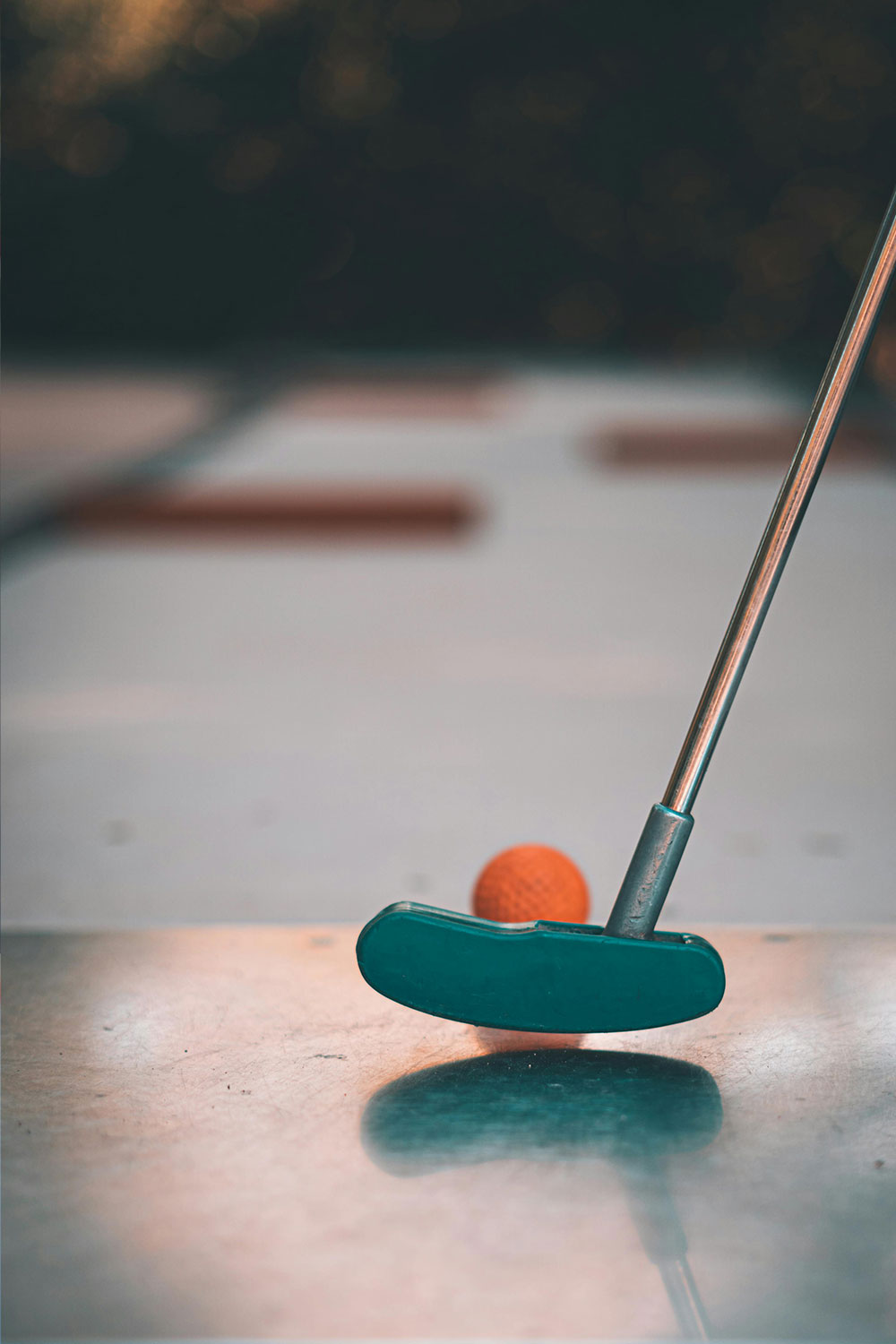 close-up di una mazza da minigolf che sta per colpire la pallina