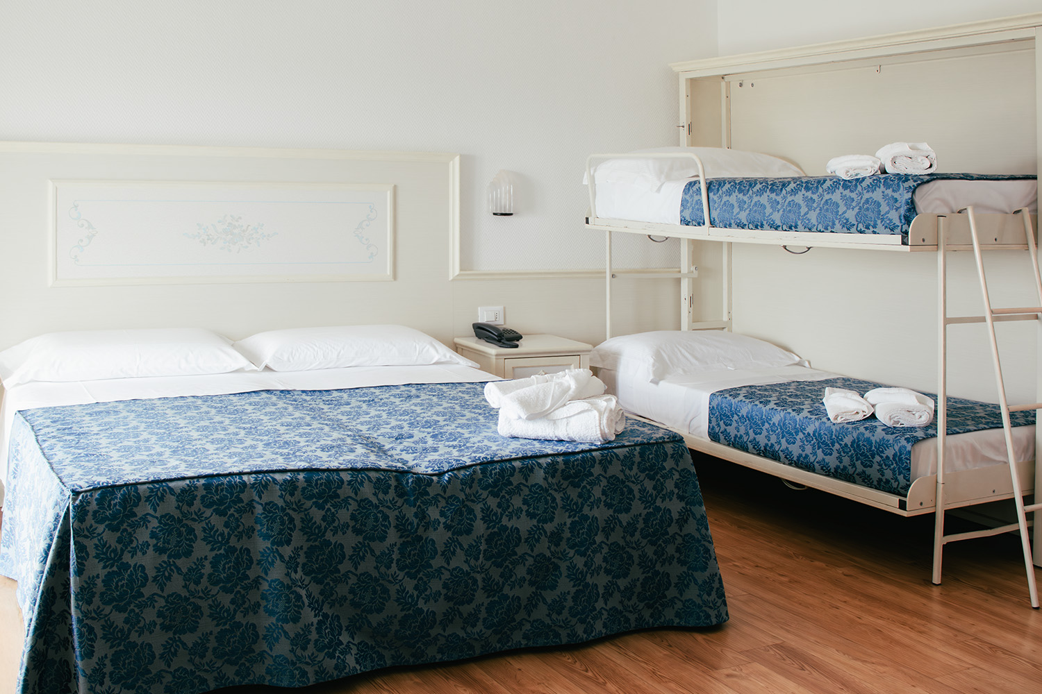 letto matrimoniale e letto a castello della camera family con lenzuola blu e bianche